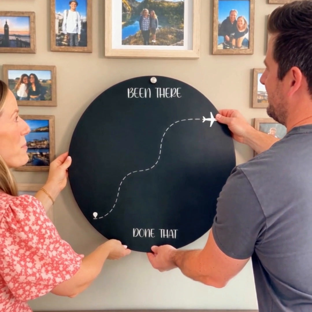 Couple setting up a Been There Done That travel magnet board on a memory wall