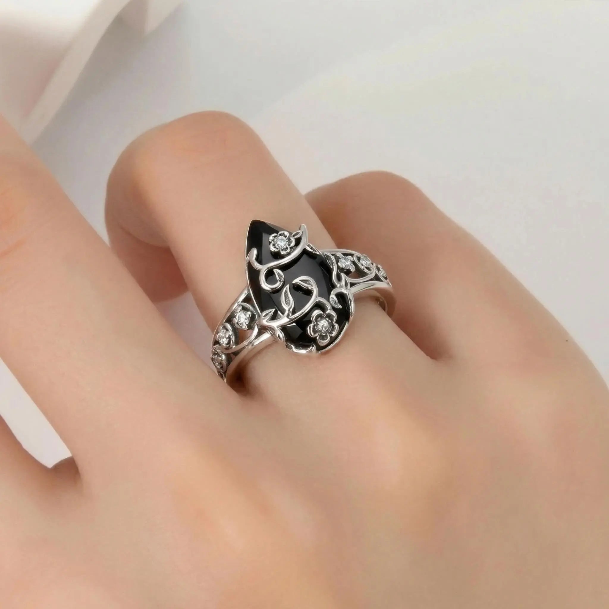 Close-up of the vintage floral black teardrop ring worn on a finger